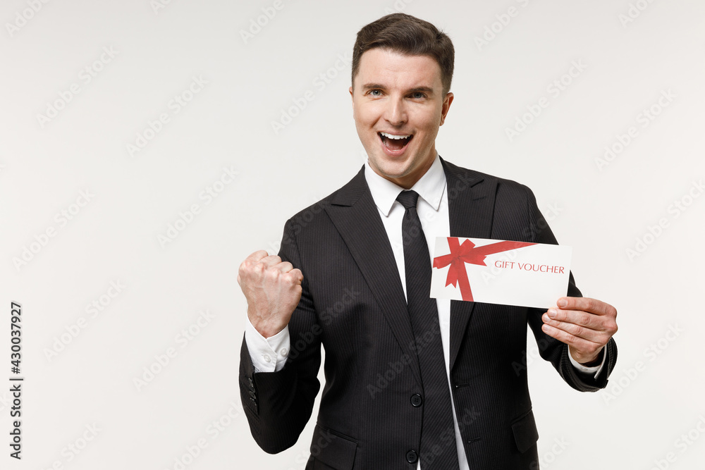 Young rich employee business corporate lawyer man in classic formal black grey suit shirt tie work in office holding gift voucher flyer mock up do winner gesture isolated on white background studio. Young rich employee business corporate lawyer man in classic formal black grey suit shirt tie work in office holding gift voucher flyer mock up do winner gesture isolated on white background studio.