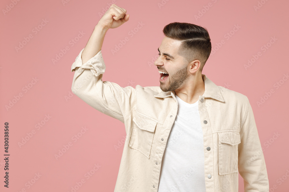 Young overjoyed happy positive trendy fun caucasian man in jacket white t-shirt do winner gesture clench fist celebrating isolated on pastel pink background studio portrait People lifestyle concept Young overjoyed happy positive trendy fun caucasian man in jacket white t-shirt do winner gesture clench fist celebrating isolated on pastel pink background studio portrait People lifestyle concept