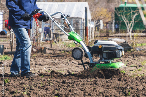 Obraz na płótnie Farmer man plows the land with a cultivator preparing the soil for sowing