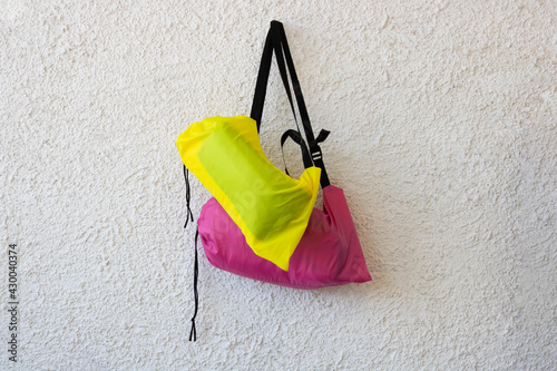 Pink and yellow sports bags with a black belt on a white rough background photo