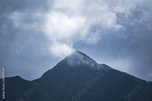 Peak of a high mountain on a cloudy and foggy day. Mountain range. Mountaineering and nature concept.