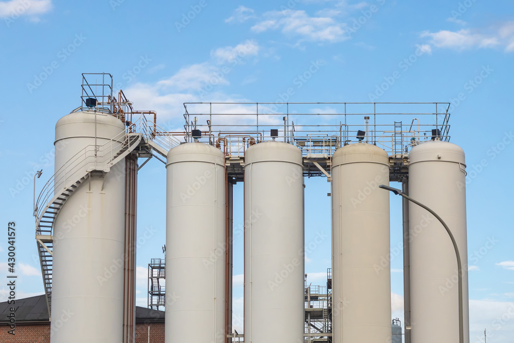 Big white vertical tanks against the sky. Large-scale chemical manufacturing