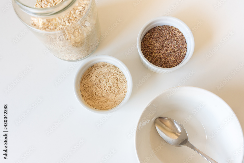 High angle closeup of bowl and spoon with oatmeal, brewers yeast and ground flaxseed (selective focus)