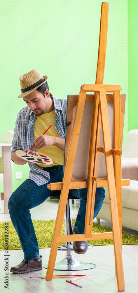 Young male artist working on new painting in his studio Young male artist working on new painting in his studio