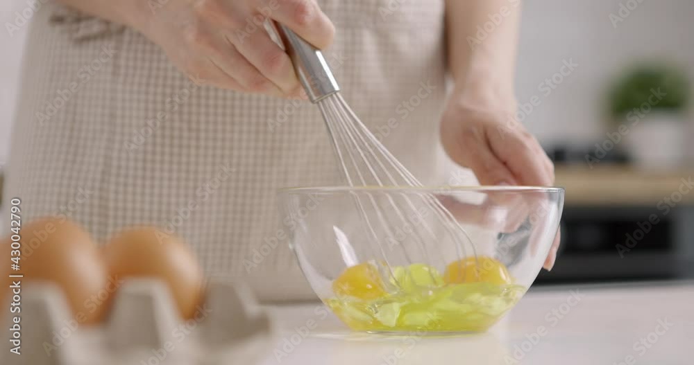Young woman stirring eggs with hand mixer, close-up. Cooking at home kitchen. Slow motion Young woman stirring eggs with hand mixer, close-up. Cooking at home kitchen. Slow motion