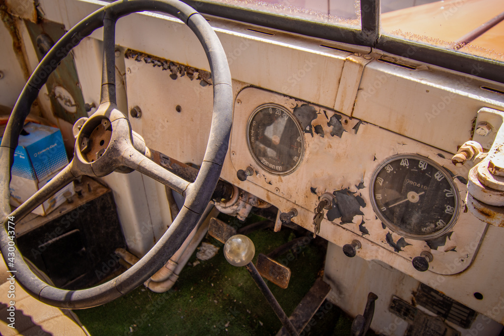 Interior of a junked retro vehicle with a dirty dash board in a junk yard.