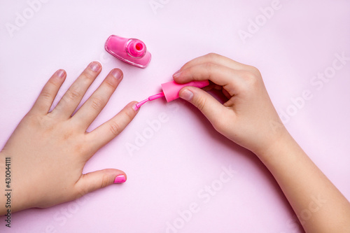 girl paints her nails with pink nail polish
