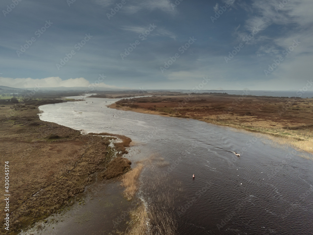 River Corrib in county Galway, Ireland. Aerial drone view. Cloudy sky. Small fishing boat.