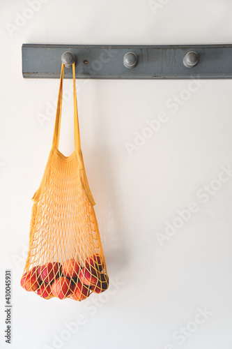 Reusable market bag with peaches hanging on an old coat rack