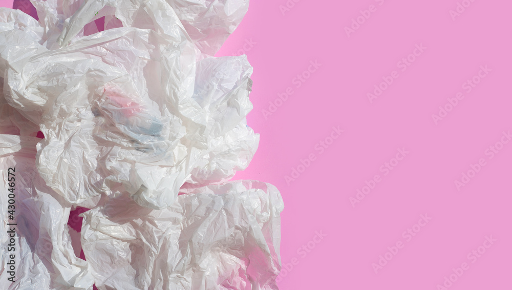 Fototapeta premium White crumpled plastic bags on pink background.