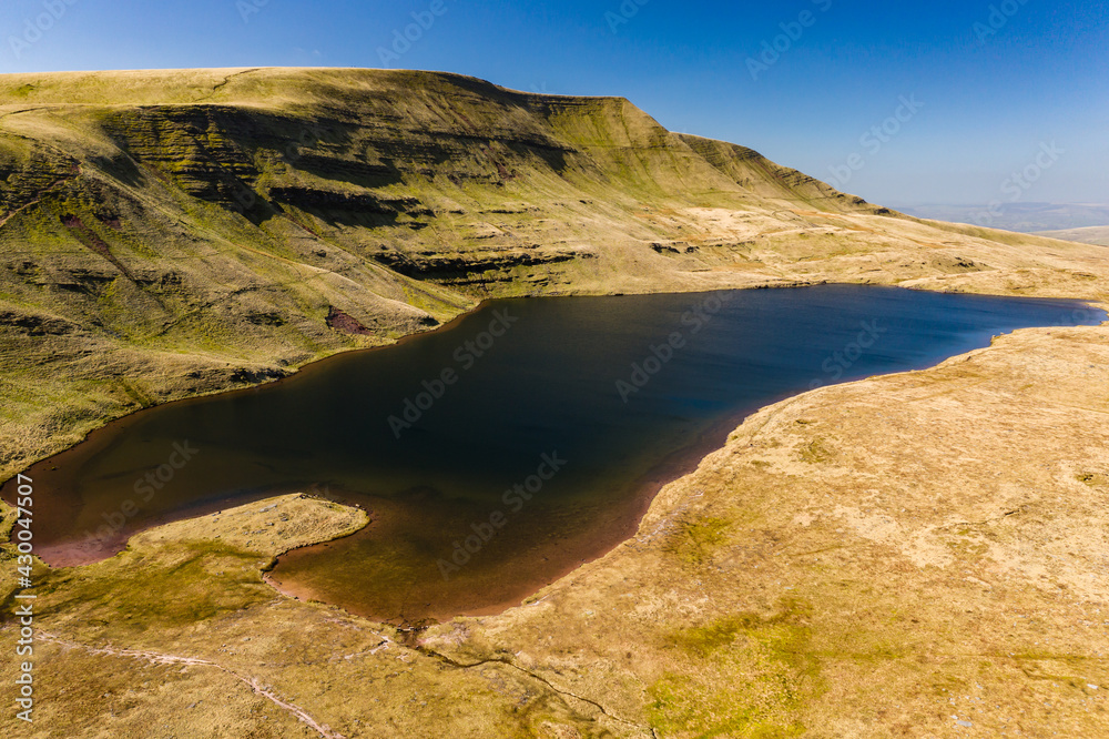 Aerial view of a beautiful glacier-formed lake at the foot of a mountain (Llan y fan Fawr)