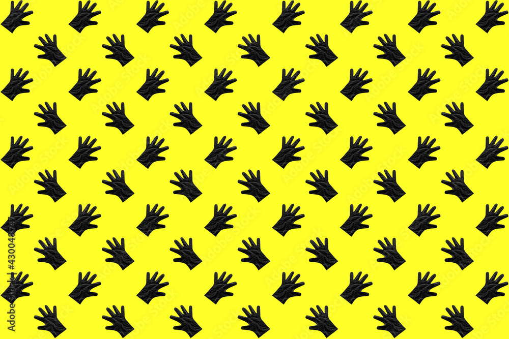 Black plastic gloves in a pattern on a yellow background Black plastic gloves in a pattern on a yellow background