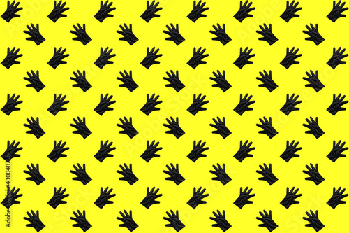 Black plastic gloves in a pattern on a yellow background