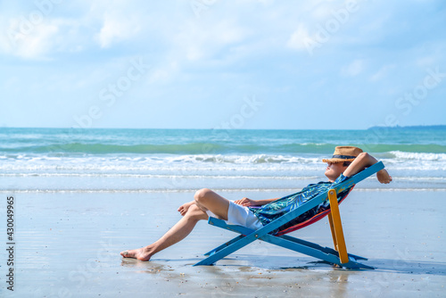 Leinwand Poster Asian man resting on beach chair at tropical beach