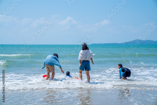 Happy Asian family on summer holiday vacation. Father and mother with two child girl kid playing together on the beach. Mom and dad with little daughter enjoy and having fun outdoor lifestyle activity © CandyRetriever 