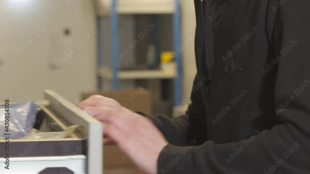 Close up of man's hands counting screws out of a neatly arranged drawer in industrial workplace, then closing the drawer Close up of man's hands counting screws out of a neatly arranged drawer in industrial workplace, then closing the drawer