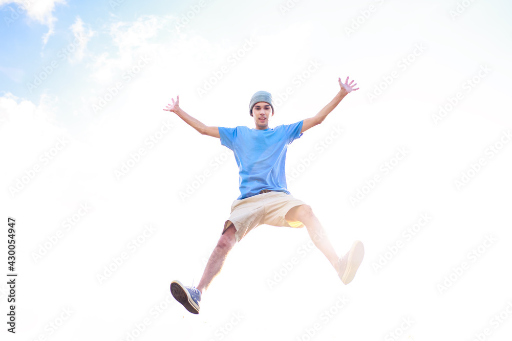 Young man jumping and celebrating with his arms raised and the  sky in the background. Man jumping for joy and feeling happy and free. Success and happiness concept.