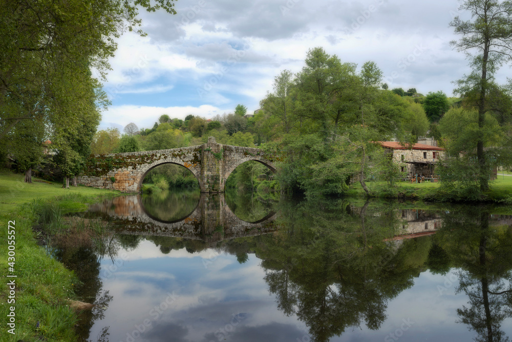 Fototapeta premium Old Romanesque stone bridge over the Arnoia river in the beautiful village of Allariz, Galicia.