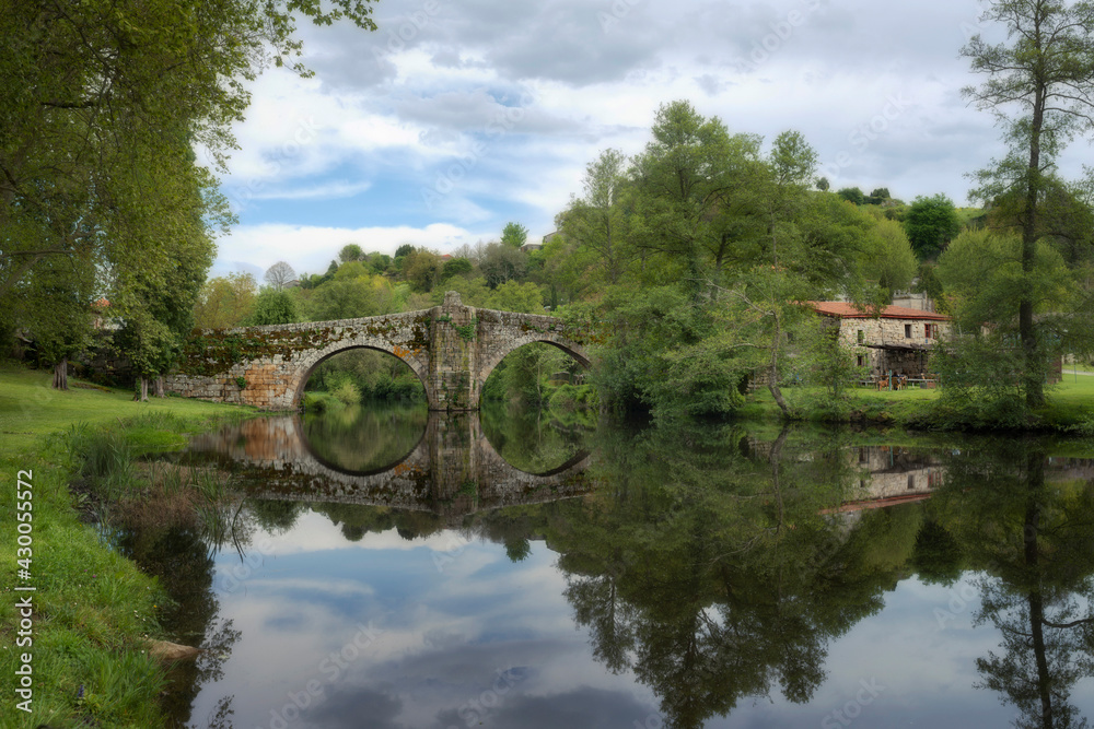 Old Romanesque stone bridge over the Arnoia river in the beautiful village of Allariz, Galicia.