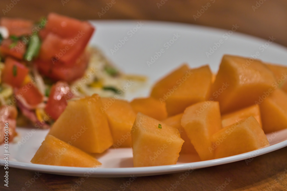 white plate with mediterranean salad and cantaloupe