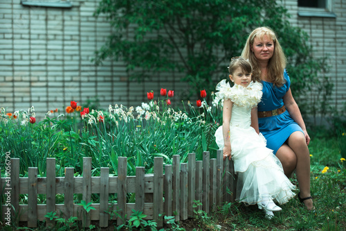 A woman with her dother little girl in an elegant dress on the street. photo