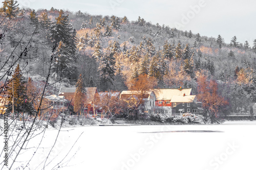 Picturesque hillside town with houses and a red barn surrounded by snow covered trees photo