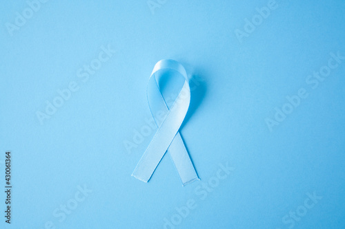 Prostate cancer awareness blue ribbon on blue background. Men healthcare concept, men carcinoma symbol.
