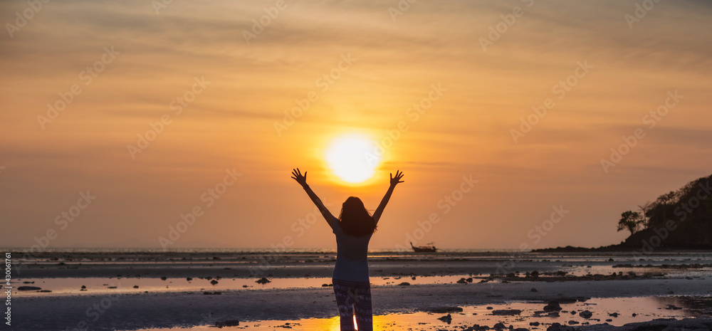 Asian woman standing on the beach by the sea at morning sky with sunrise background.
