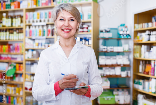 Mature female seller is checking assortment of care products in store.