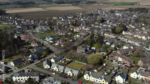 Aerial view of the Scottish town of Edzell on a sunny spring day, Angus, Scotland. Right to left rising and rotating pan over the south end of the town with zoom in. photo