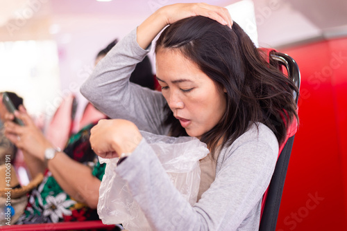 Fotografija Woman suffering from sea sickness and feeling throw up vomiting in to plasatic b