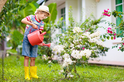 Child gardening. Boy with watering can in garden.