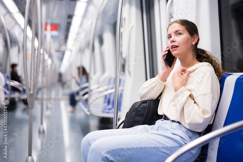 Portrait of stylish young woman holding smart phone in a subway train
