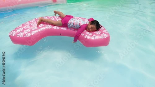 little kid swimming in pool, relaxing in the swiming pool in a summer hot day. refershing in holiday, a pink float enjoying the summer photo