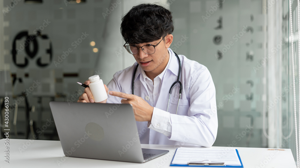 Medical, a male doctor attending online meeting pointing at the pill bottle to explain the pill’s properties. Medical, a male doctor attending online meeting pointing at the pill bottle to explain the pill’s properties.