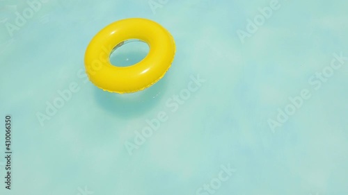 yellow dounut ring in blue water, swimingpool in summer sunny day. fresh water in the resort. yellow swimming pool ring float in blue water. relaxing in the swimming pool on a summer hot day.  photo