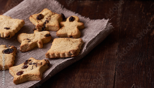 Healthy homemade gluten-free, lactose-free cookies of various shapes without sugar with raisins and chocolate on a dark brown wooden background