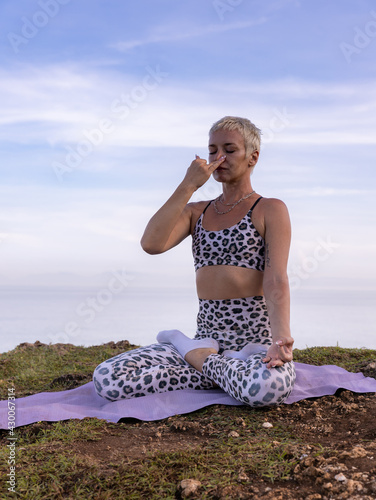 Yogi woman sitting in lotus pose, practicing Anuloma Viloma Pranayama, Alternate Nostril Breathing. Control prana, control of breath. Sunrise time. Yoga retreat. Bali, Indonesia photo