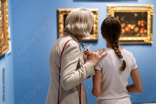 фотографія Attentive tween girl with senior woman looking with interest at gallery expositi