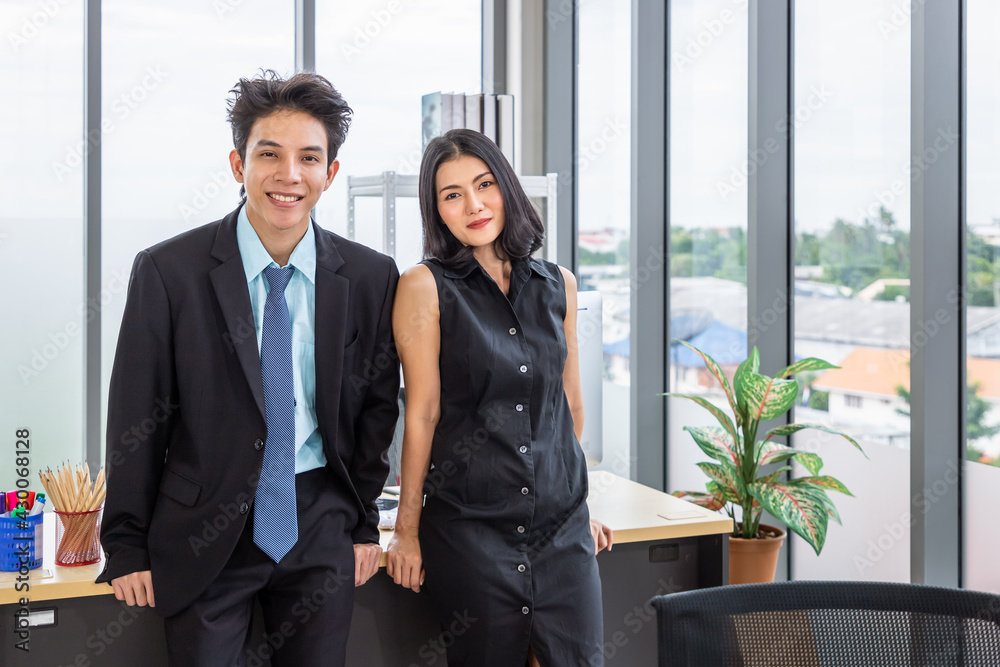 Asian businessman and businesswoman discussing with computer at desk, working together at workplace office, looking at camera. Asian businessman and businesswoman discussing with computer at desk, working together at workplace office, looking at camera.