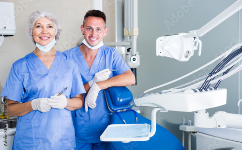 Portrait of professional cheerful dentists standing in modern medical office