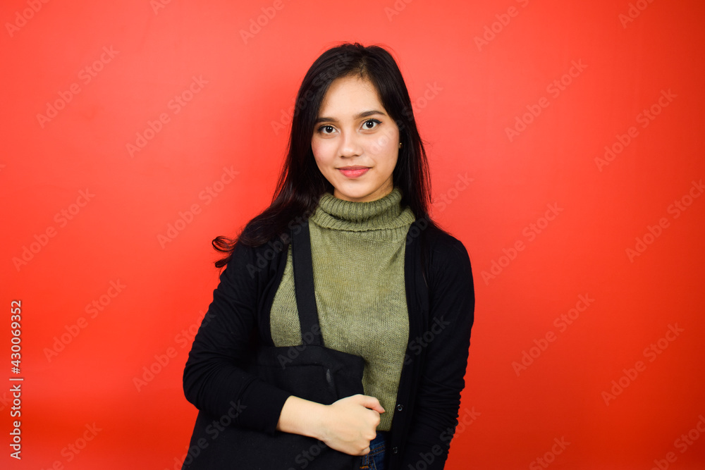 Fototapeta premium Smiling and look at camera of Young beautiful asian women using black sweater with red isolated background