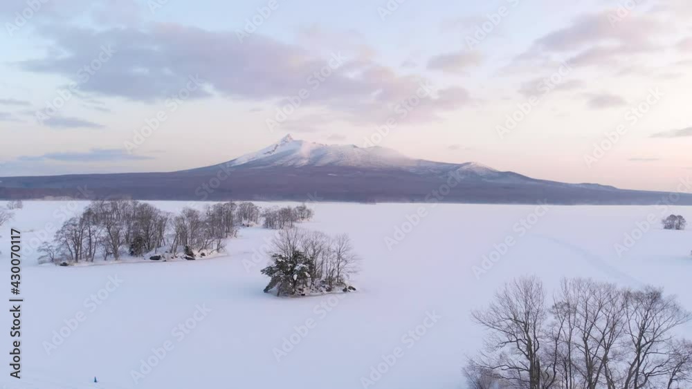 Drone slowly pulling back from beautiful snowy landscape over frozen lake Drone slowly pulling back from beautiful snowy landscape over frozen lake