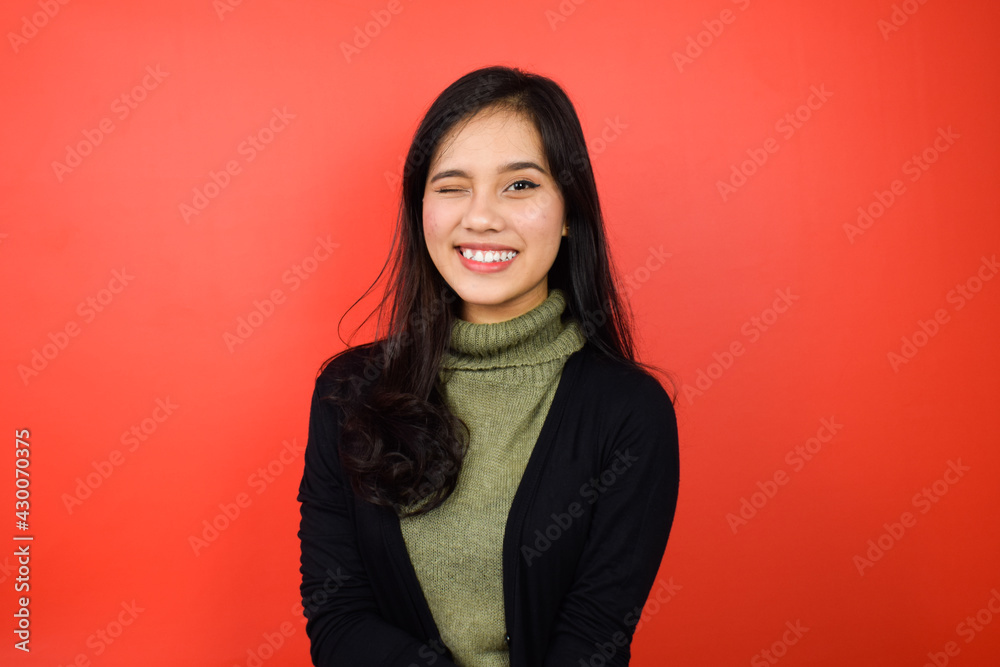 Smiling and look at camera of Young beautiful asian women using black sweater with red isolated background Smiling and look at camera of Young beautiful asian women using black sweater with red isolated background