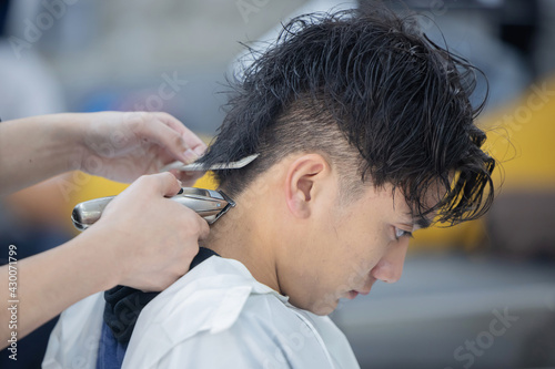 Hairdresser Cutting Customer Hair with Hair Clipper
