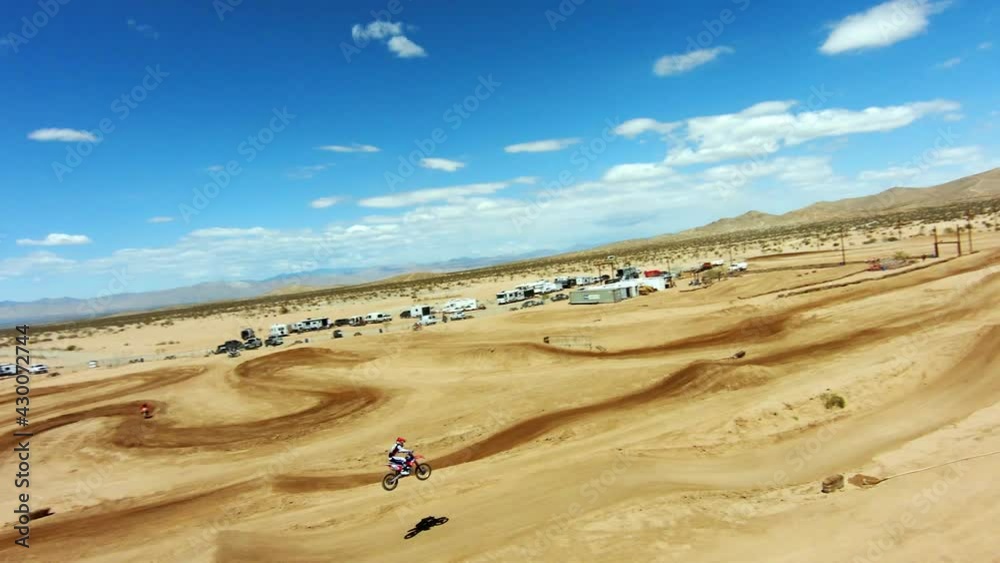 Aerial view of a motorcycle making a long jump at a race track in the desert - slow motion Aerial view of a motorcycle making a long jump at a race track in the desert - slow motion