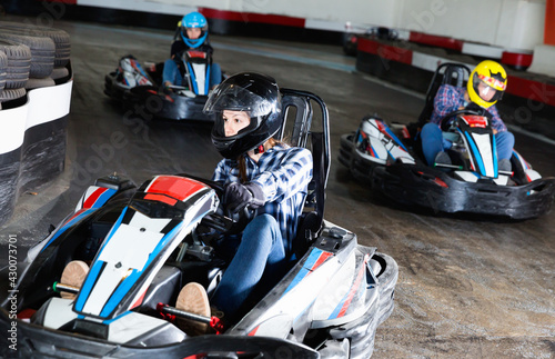 Group of glad cheerful smiling people driving go-carts at racing track