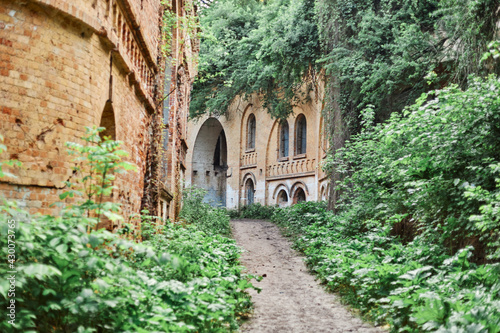 Road with puddles after rains  old ancient abandoned buildings with brick green plants  beautiful landscape beautiful nature  traveling  tourism.