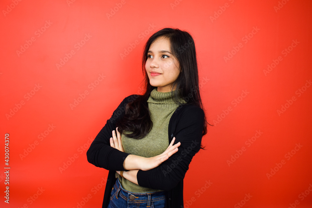Portrait of Young beautiful asian women using black sweater crossed arms and smile with red isolated background