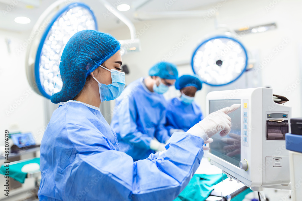 Anesthesiologist keeping track of vital functions of the body during cardiac surgery. Surgeon looking at camera. Doctor checking monitor for patient health status. Anesthesiologist keeping track of vital functions of the body during cardiac surgery. Surgeon looking at camera. Doctor checking monitor for patient health status.